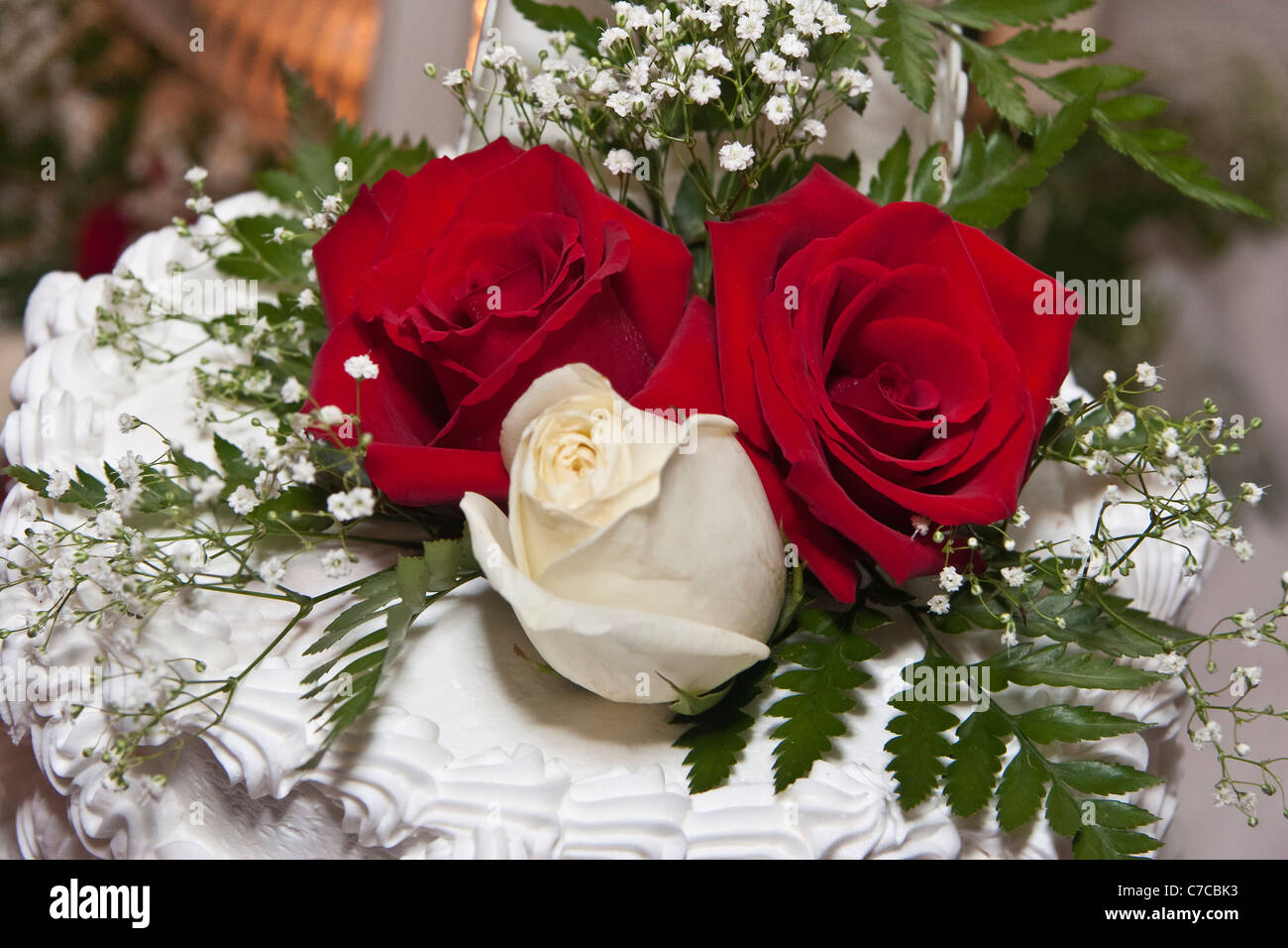 Top layer of wedding cake decorated with white and red roses Stock Photo