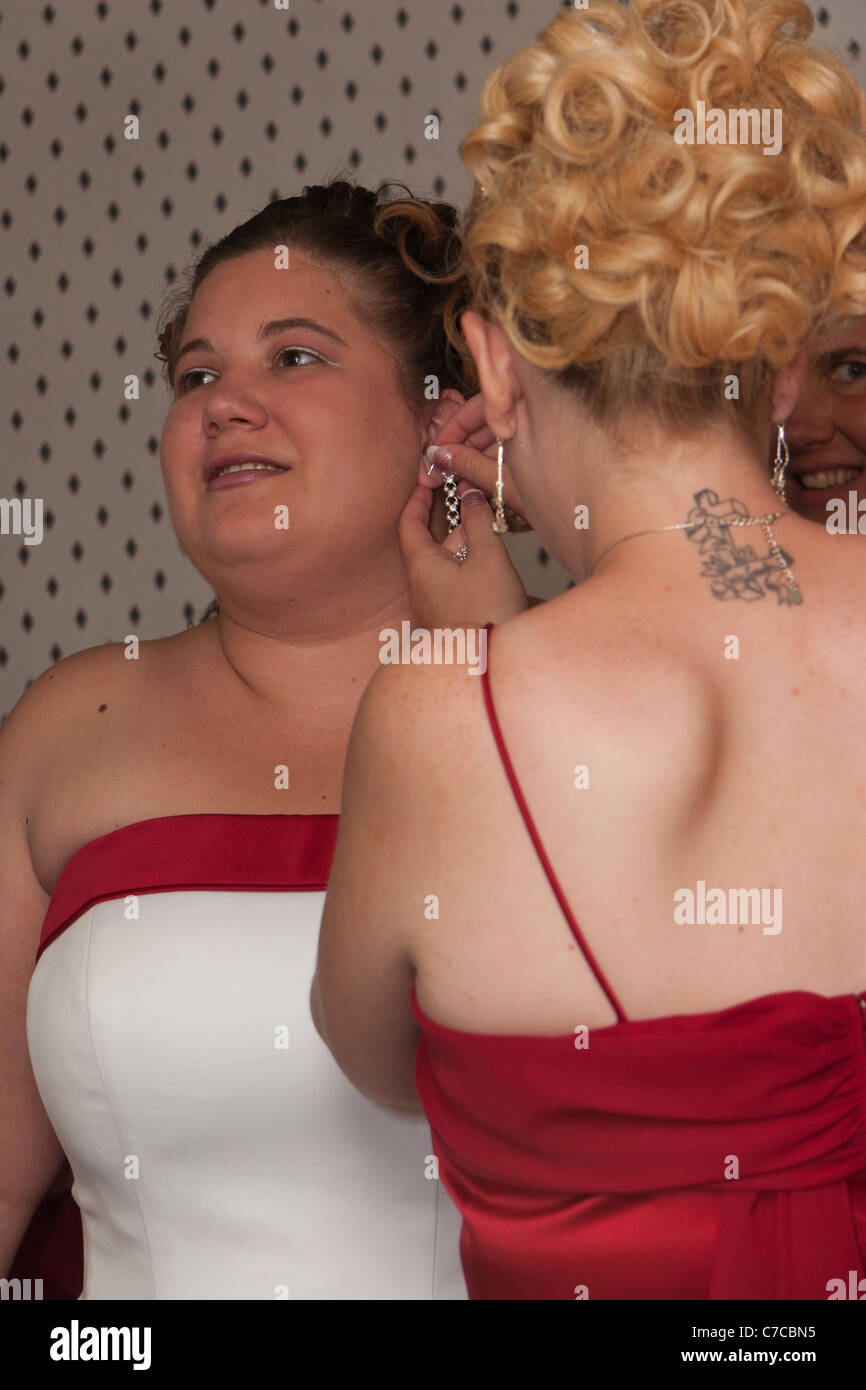 Bridesmaid helping the bride with putting earrings on Stock Photo