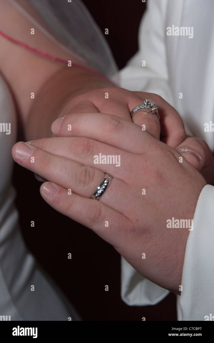 Newly wed couple holding hands and showing off their wedding bands Stock Photo