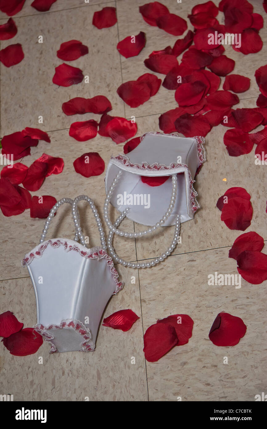 Loose Red roses petals spread over the floor during wedding reception and two small white baskets Stock Photo