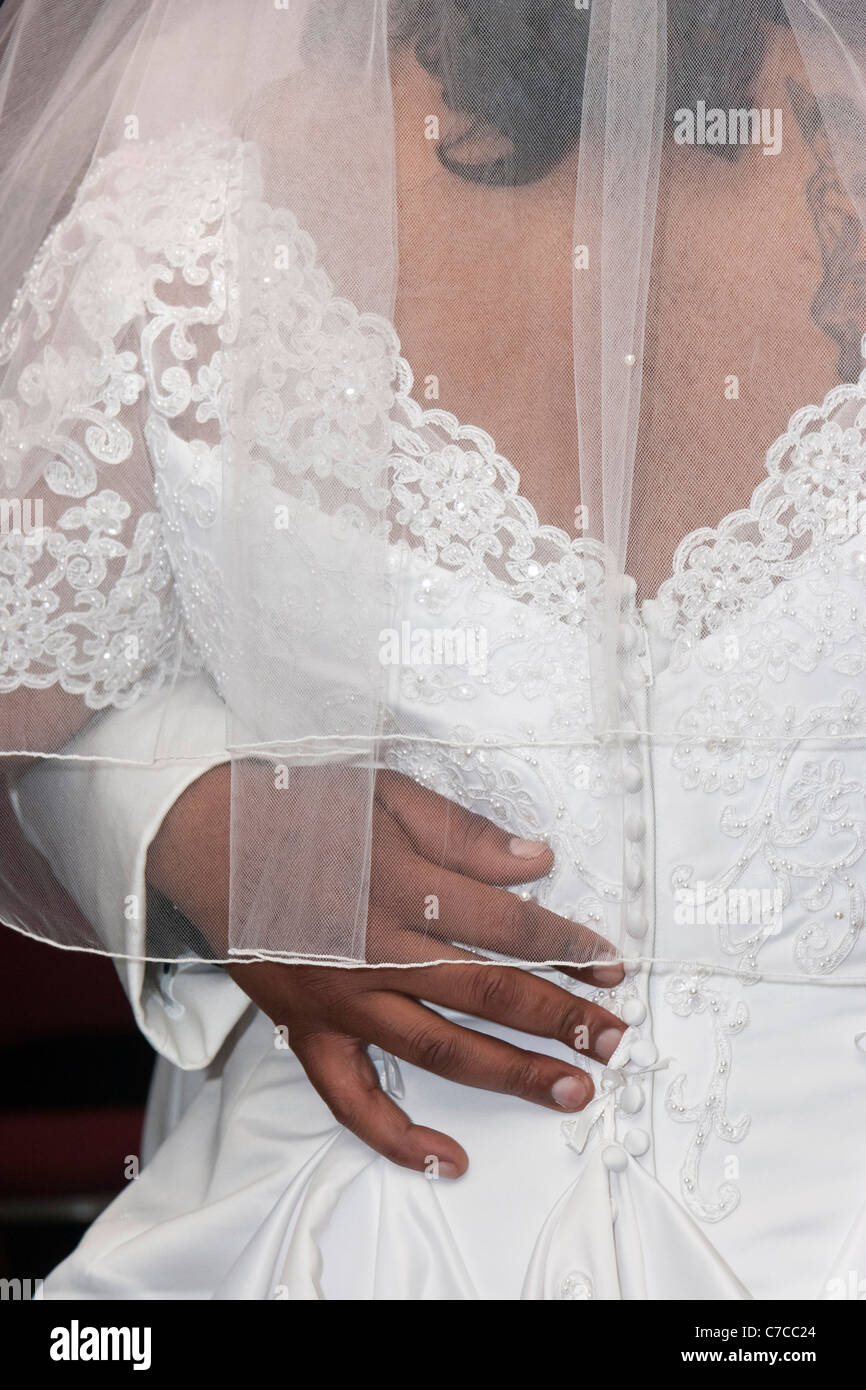 A back view of grooms hand under the veil holding his bride during first dance Stock Photo