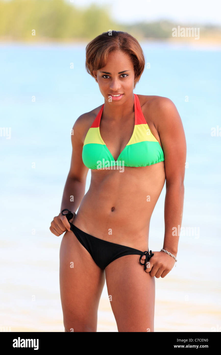 A Young beautiful black woman in a multi color bikini top and black bikini  bottom poses at the beach Stock Photo - Alamy