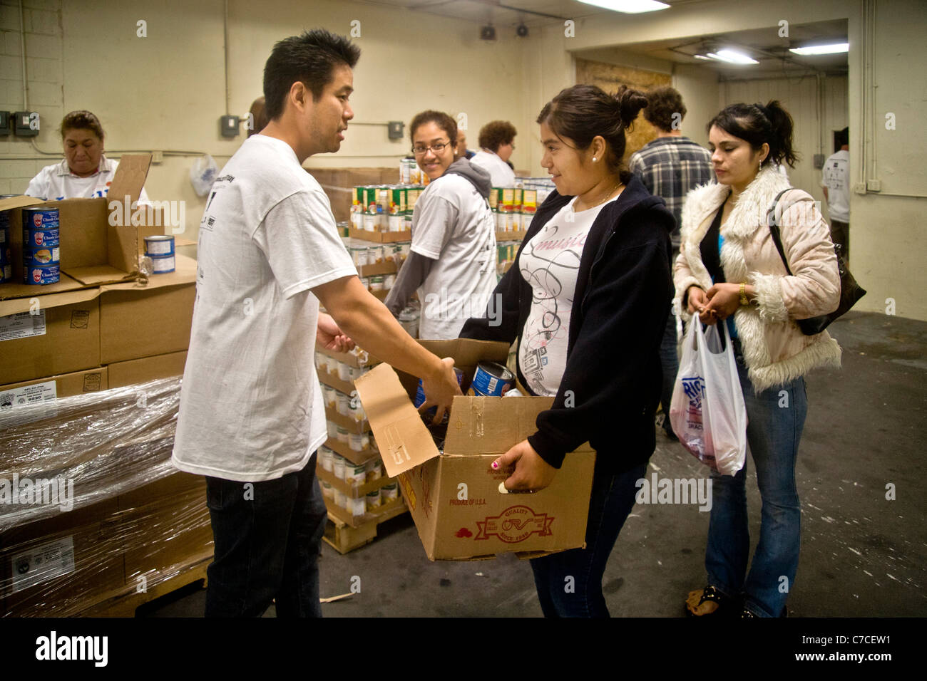 Hispanic and Caucasian volunteers give food to a young woman at a charity food distribution in Santa Ana, CA. Stock Photo