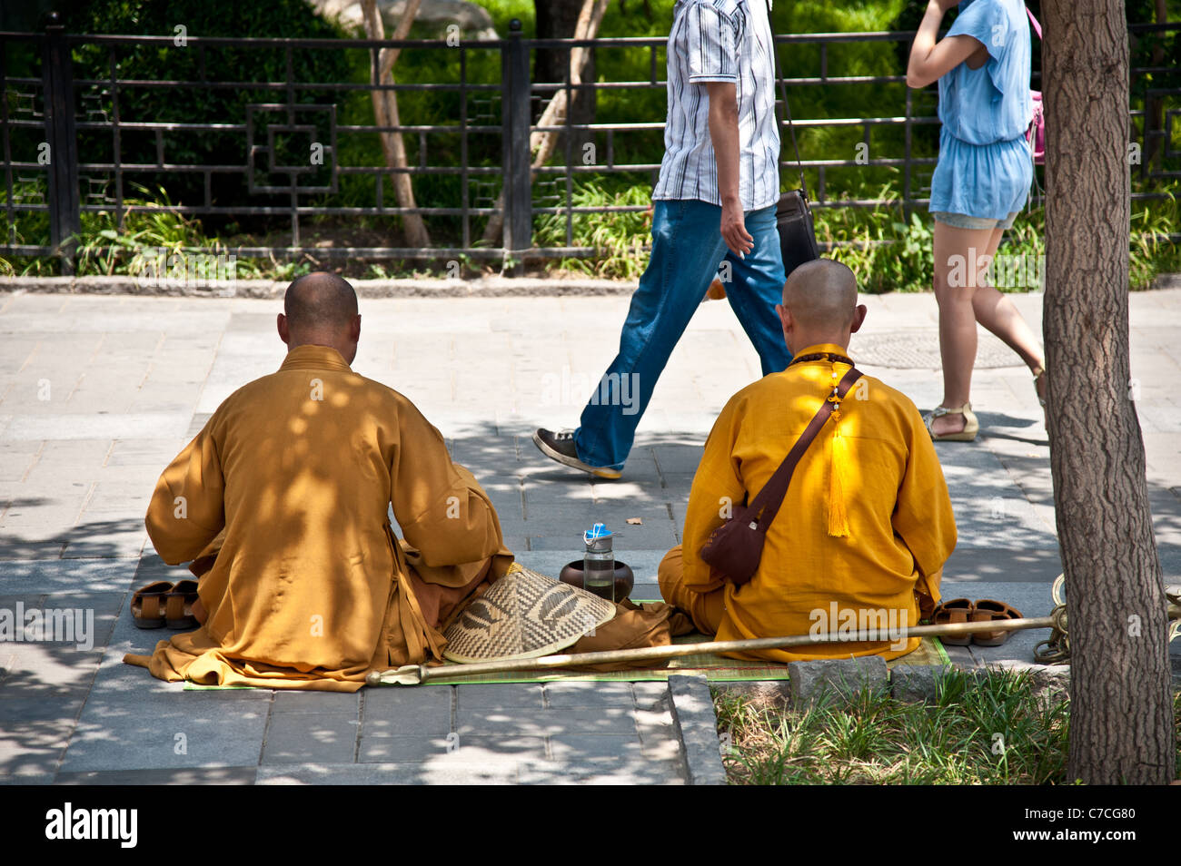 Monks in yellow ropes resting at a busy Beijing Street Stock Photo