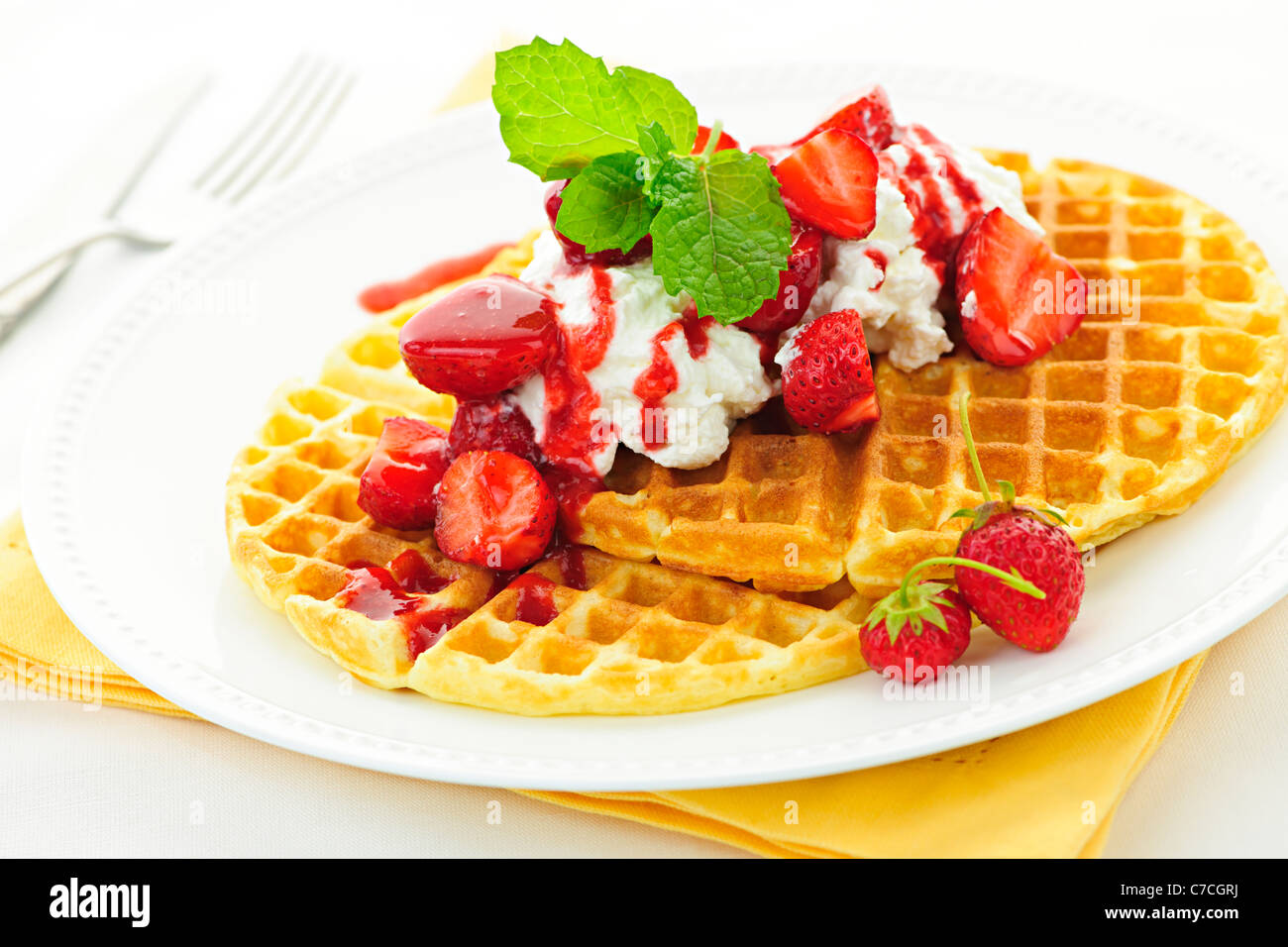 Plate of belgian waffles with fresh strawberries and whipped cream ...