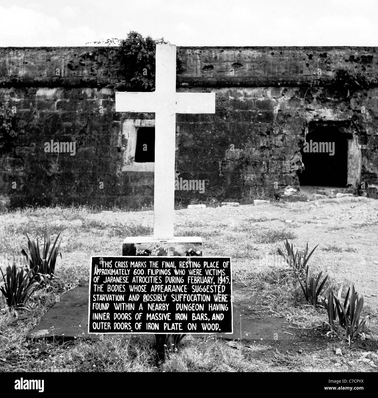 1950s, Philippines, Fort Santiago, Manila, WW2 war memorial, a white cross with inscription plate marking the final resting place of those who died. Stock Photo