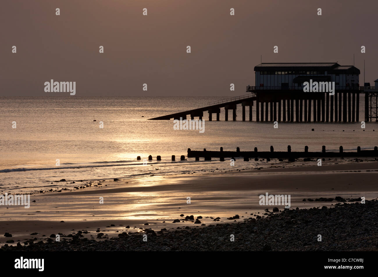 Cromer beach at sunrise in Summer with the lifeboat station on the pier in Norfolk England Stock Photo