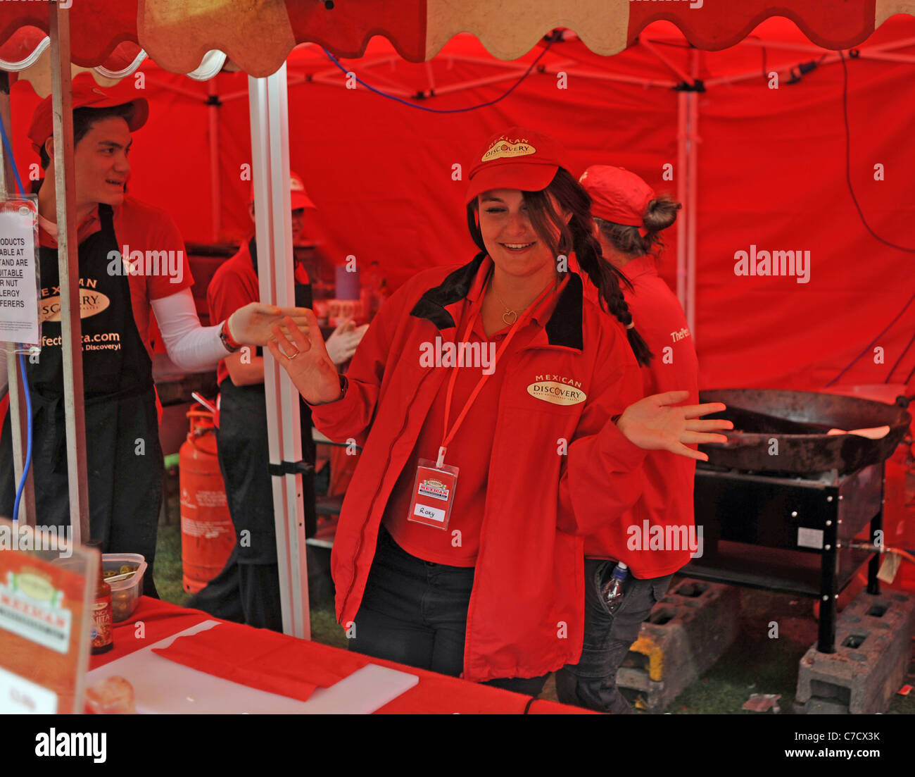 Girl wearing red serving at a Mexican food stall at the Fiery Food Festival in Brighton UK food stall Stock Photo