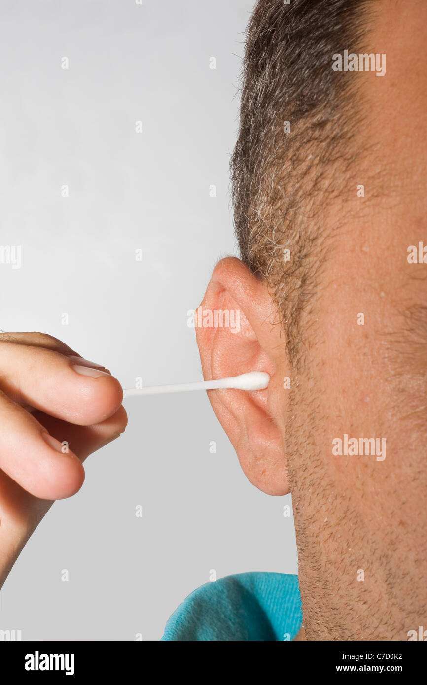 handsome young man cleaning ears with cotton pad stick. isolated on white background Stock Photo