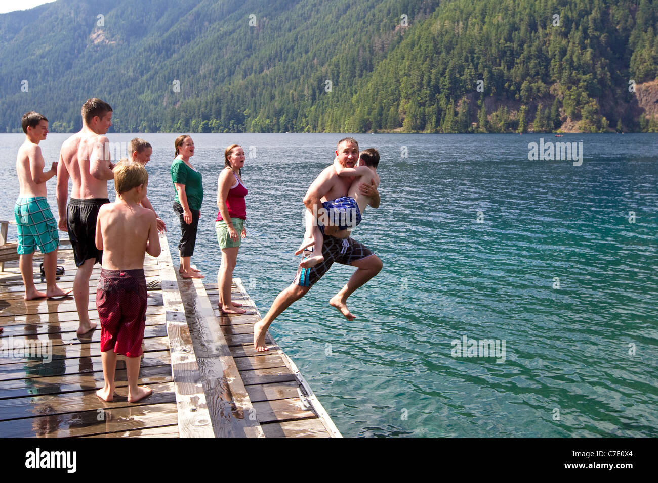 Father leaps into lake water with son, summer fun family Stock Photo