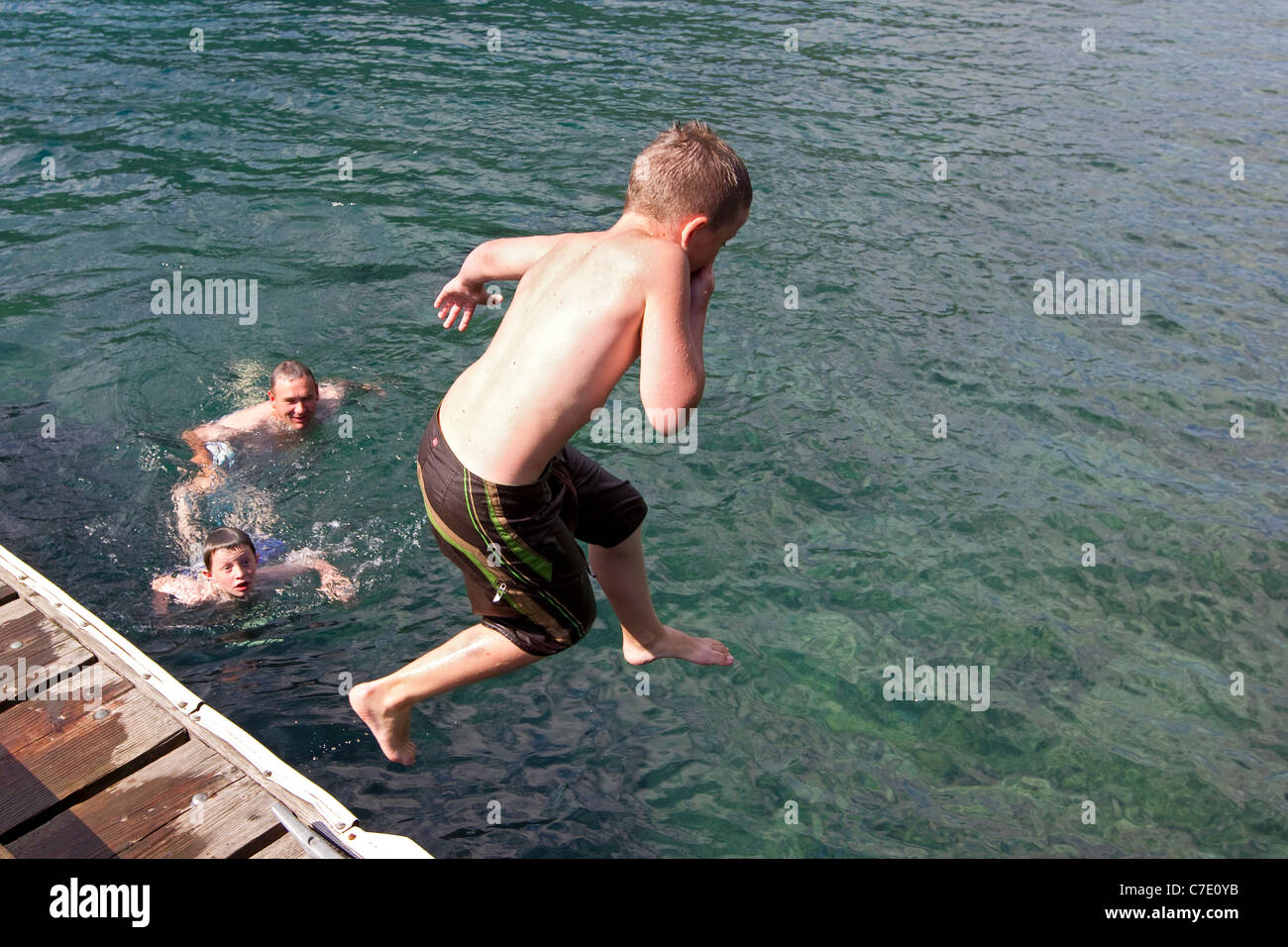 Boy leaps into lake from dock, summer fun family Stock Photo