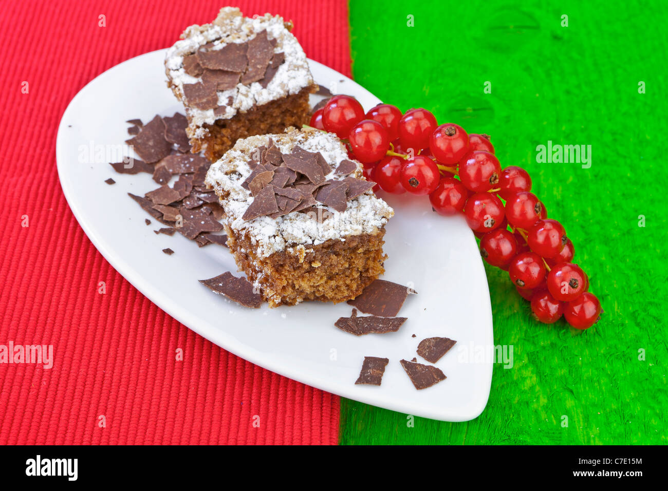 Chocolate cake with icing and chocolate shavings, served with red currants. Stock Photo