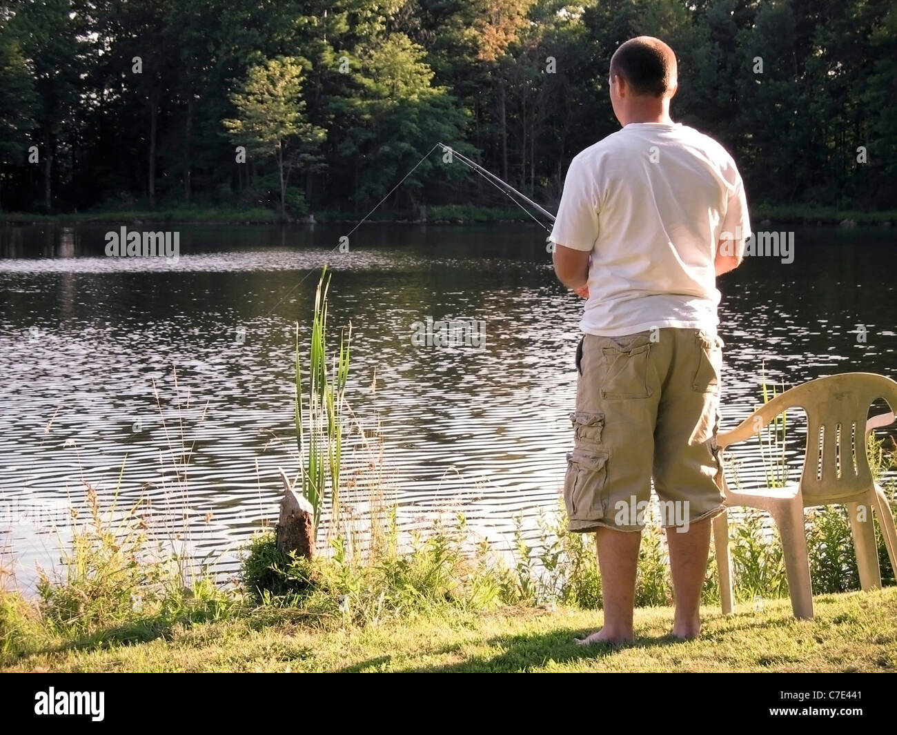 A lone fishermen fishing in a rural pond. Stock Photo