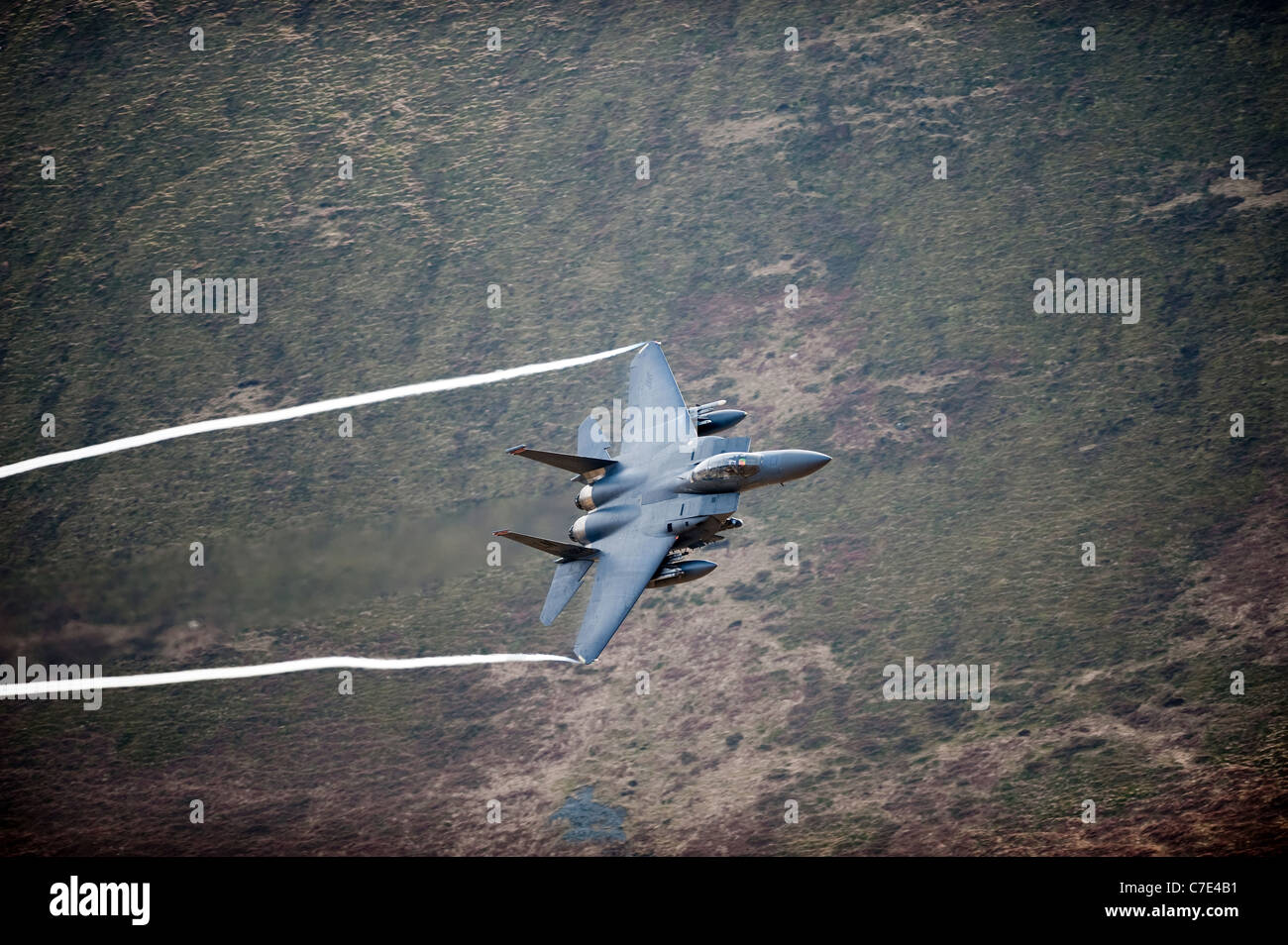 USAF F-15E Strike Eagle makes a turn during a low flying flight in mid Wales shot from the hill side Stock Photo
