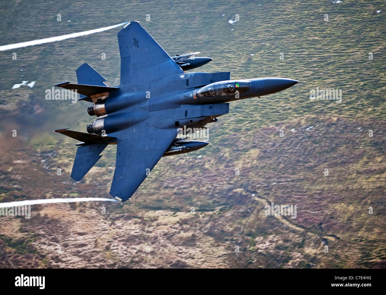 USAF F-15E Strike Eagle makes a turn during a low flying flight in mid Wales shot from the hill side Stock Photo
