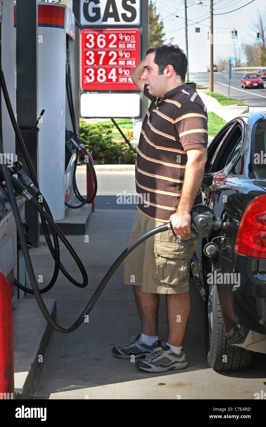 A man pumping high priced gas into his car with a disgusted look on his face. Stock Photo