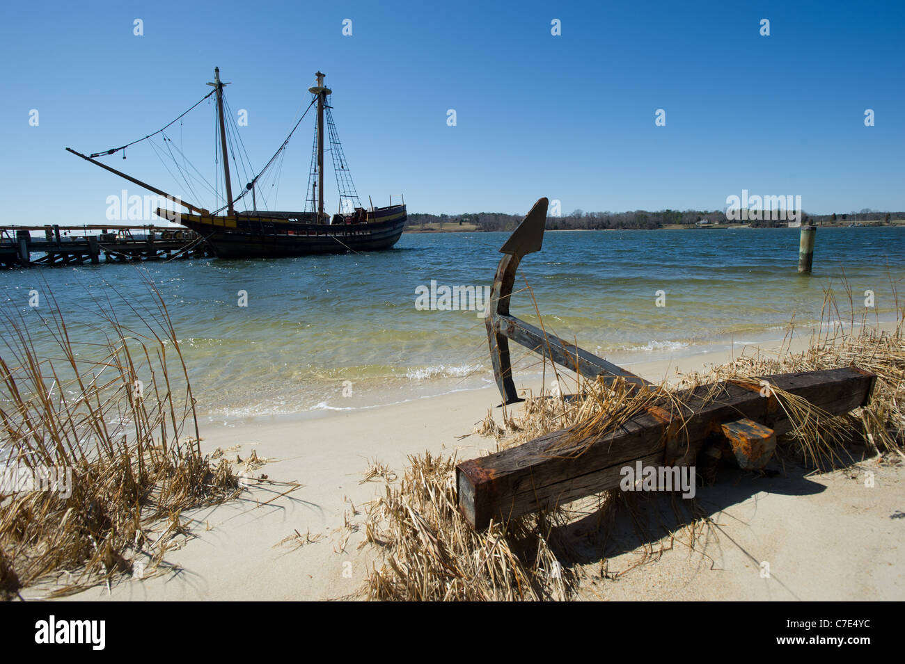 Anchor on a beach with ship docked in background Stock Photo