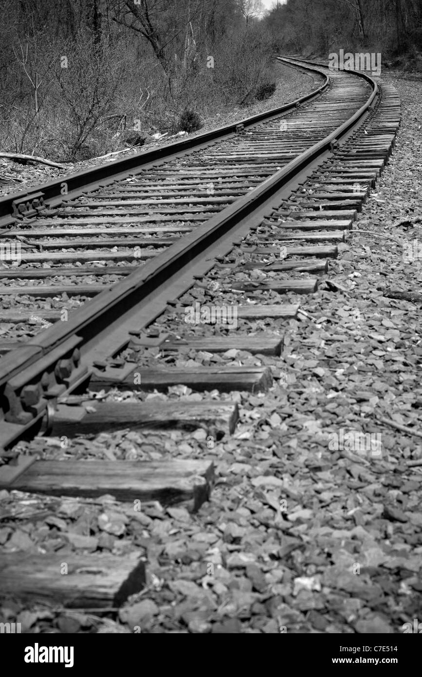 Railroad tracks curving off into the distance ahead - black and white Stock Photo