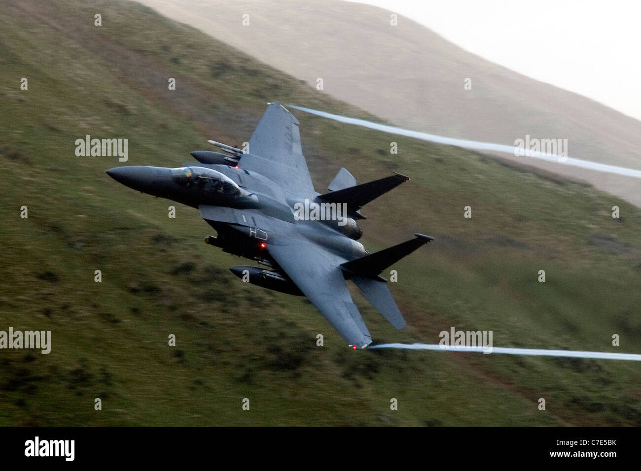 USAF F-15E Strike Eagle makes a turn mountains of Snowdonia in the background during a low flying flight Stock Photo