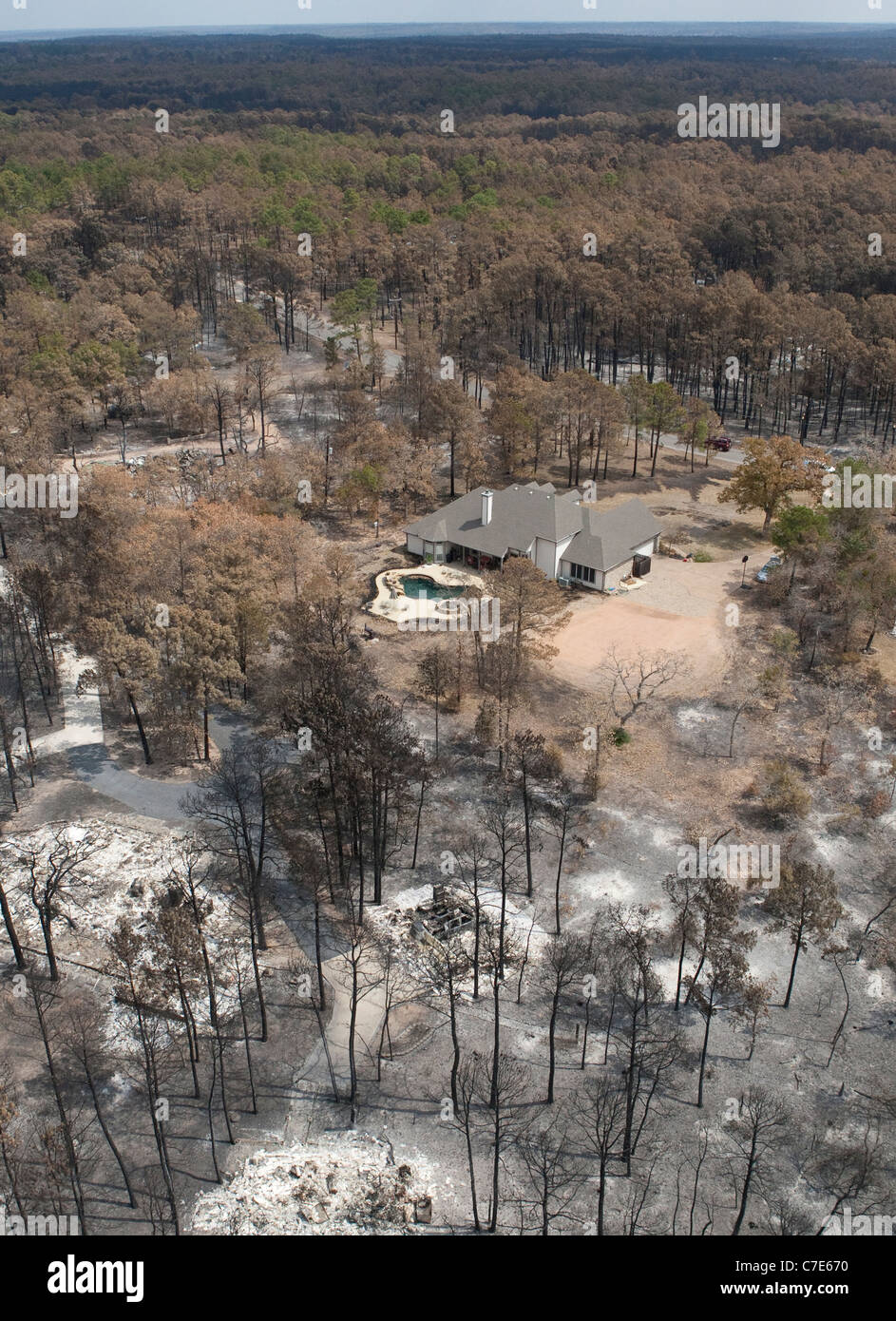 Aerial view of undamaged home surrounded by land devastated by wildfires near Bastrop, Texas, in the wake of a long drought Stock Photo