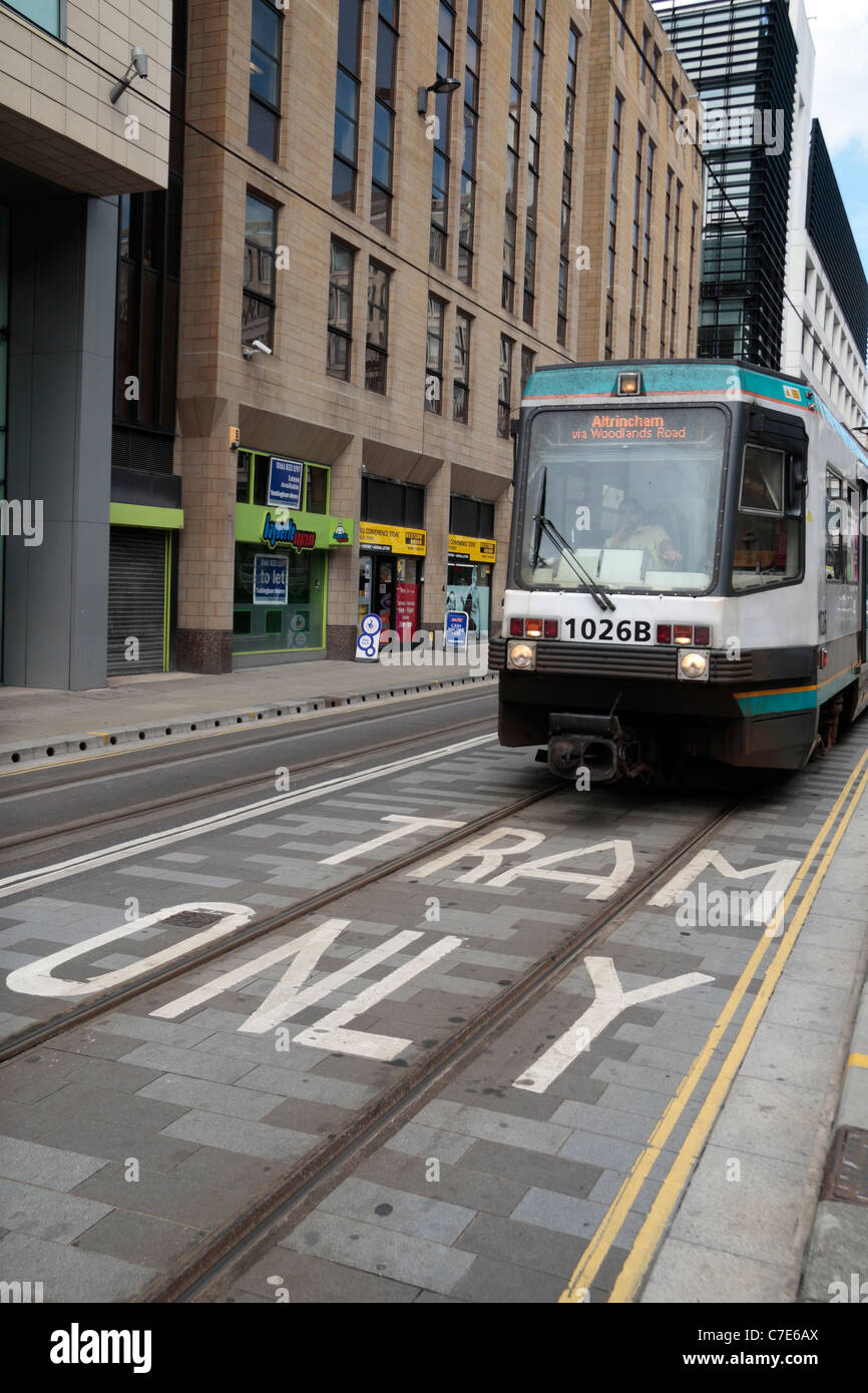 A Manchester Metrolink tram moving over a 'Tram Only' sign on the road in Manchester, UK. Stock Photo