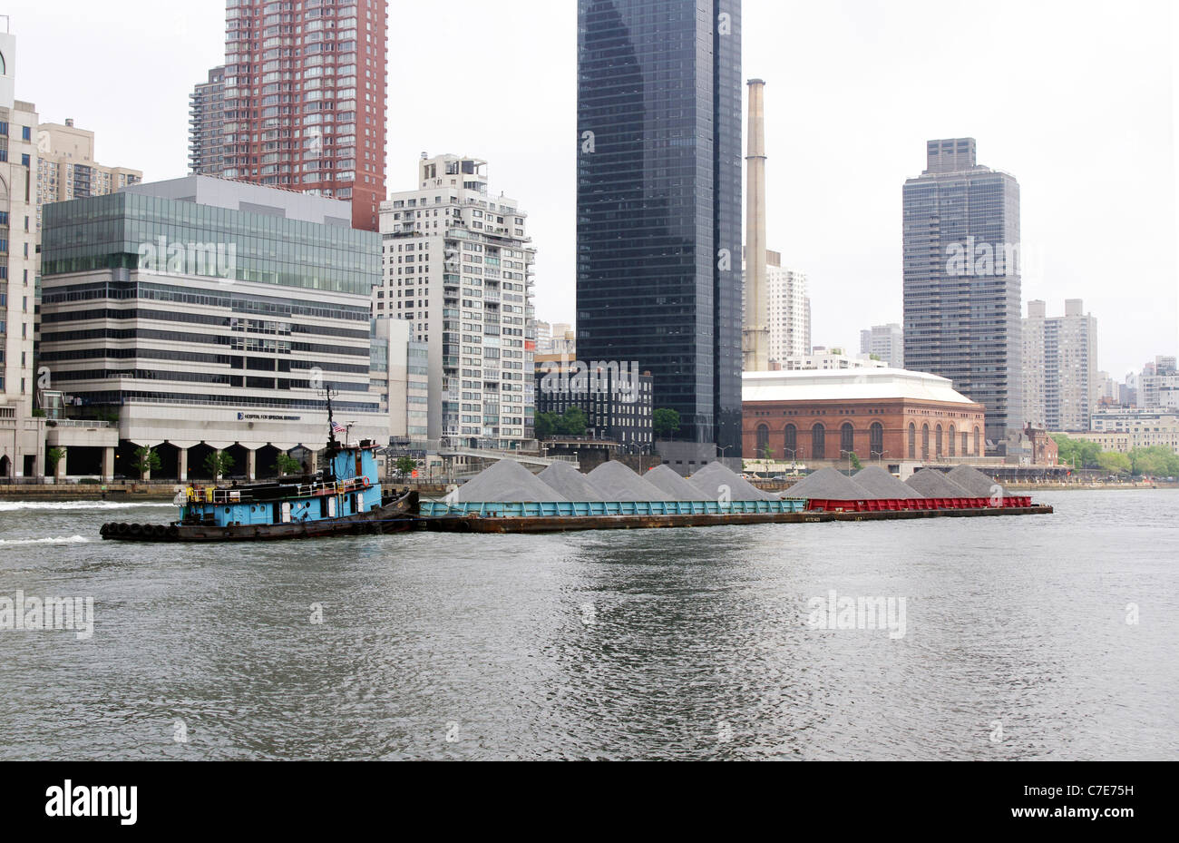 Tug boat pushing two gravel filled barges up the West channel of the East River, Manhattan, New York City Stock Photo