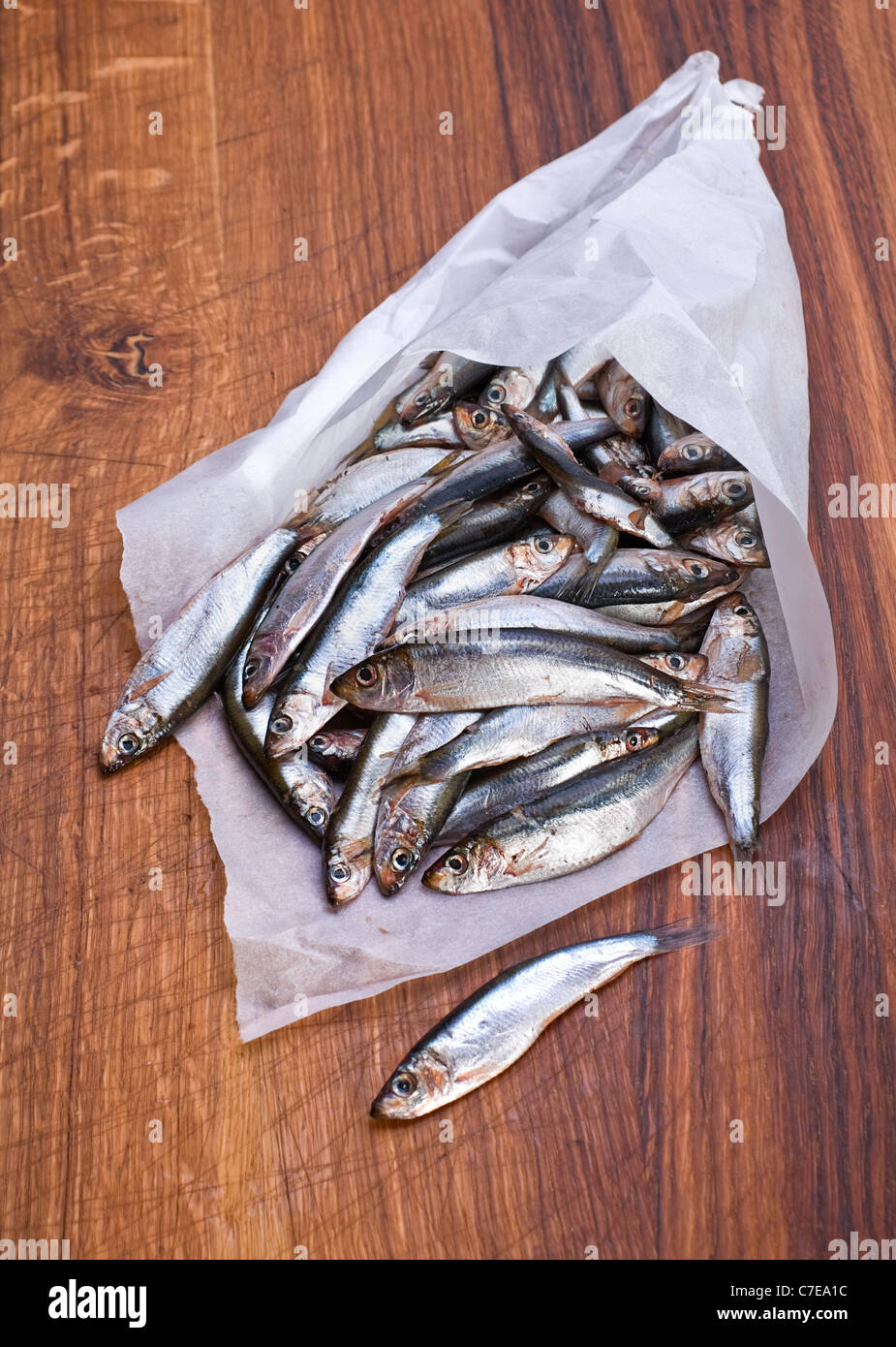Salted spat fish in paper smal bag on wood board Stock Photo
