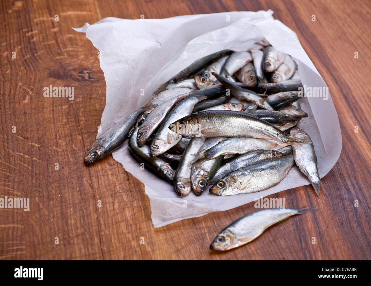 Salted spat fish in paper smal bag on wood board Stock Photo