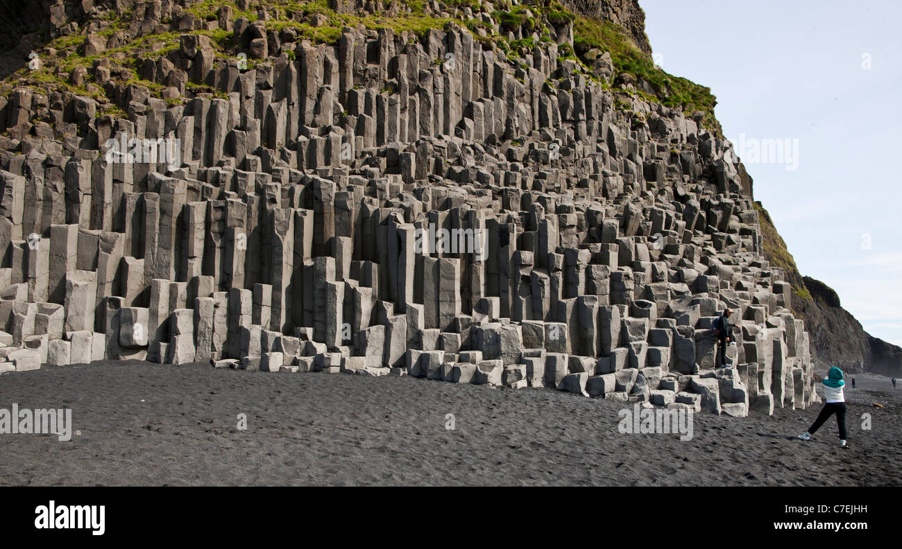 Tourists at the beach Reynisfjara, columnar basalt in the back Stock Photo