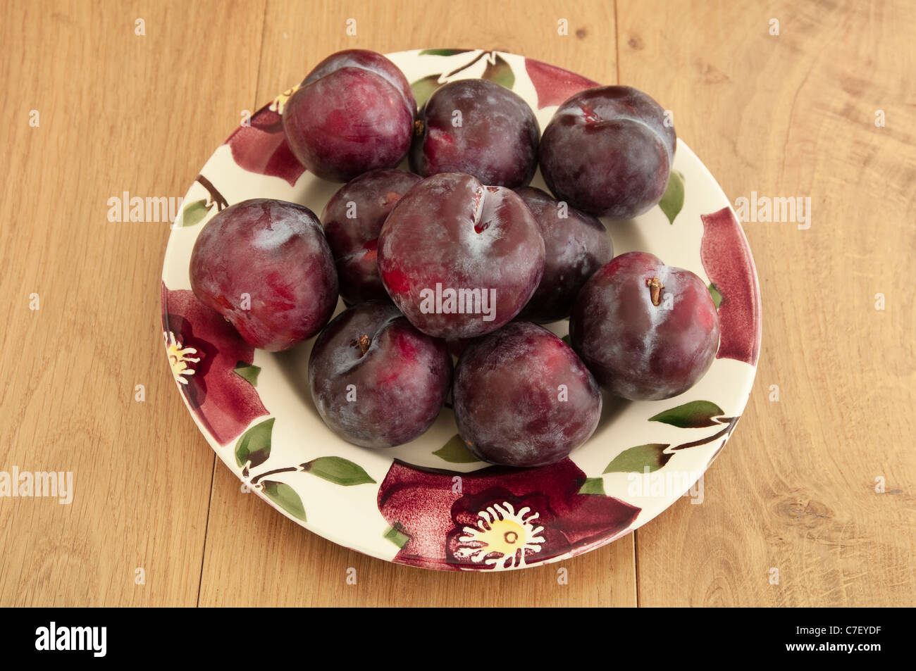Dark purple plums, on a plate - autumn / autumnal fruits. UK. Stock Photo