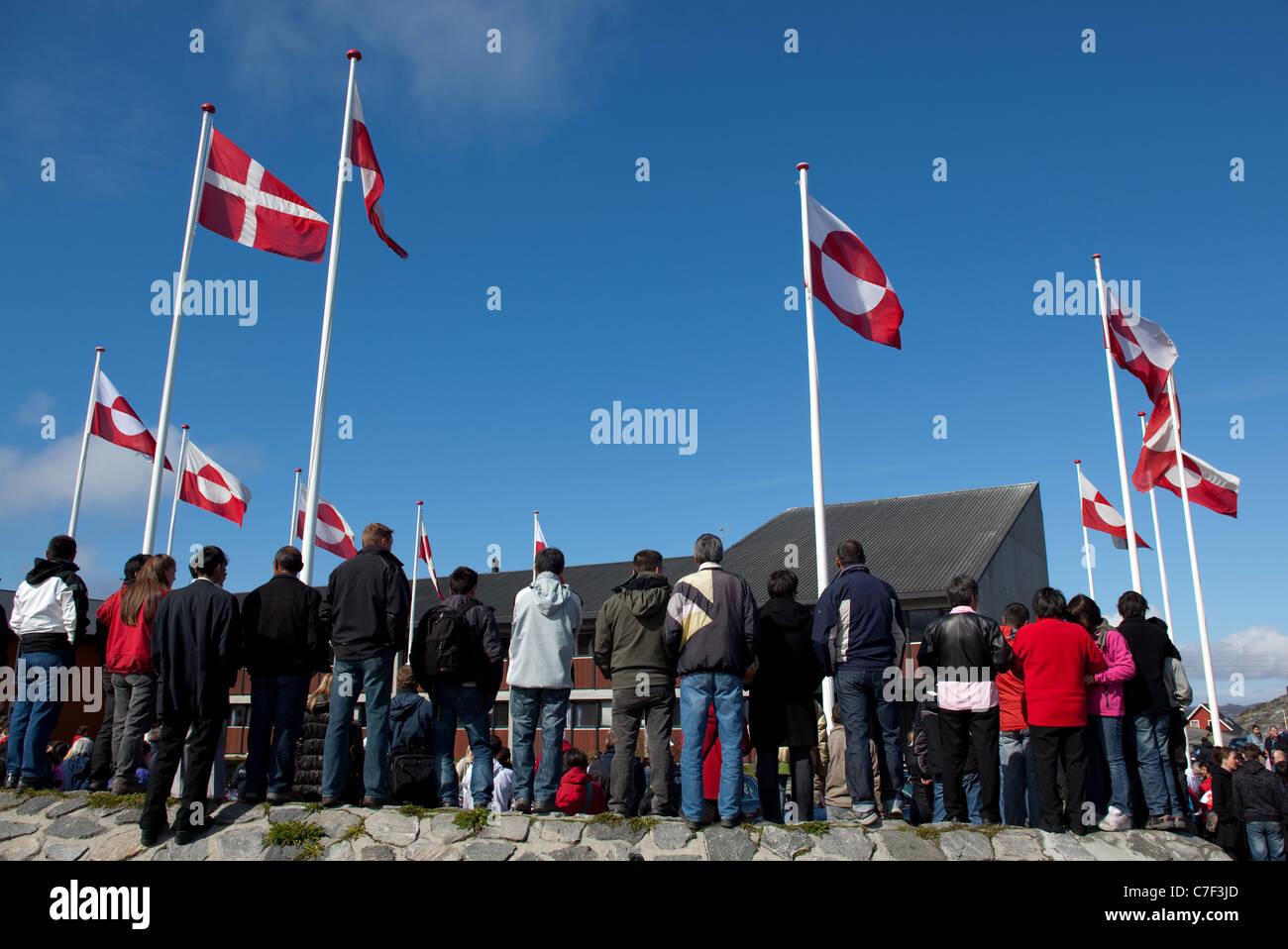 Danish and Greenland flags above people waiting to glimpse the Danish