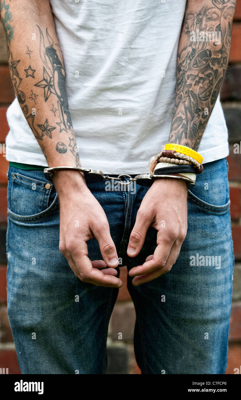 Handcuffed teenager with tattoos Stock Photo