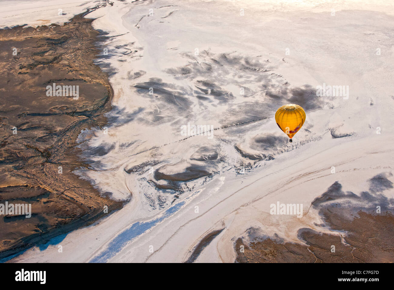Yellow hot air balloon flying low over Lake Eyre, South Australia. Stock Photo