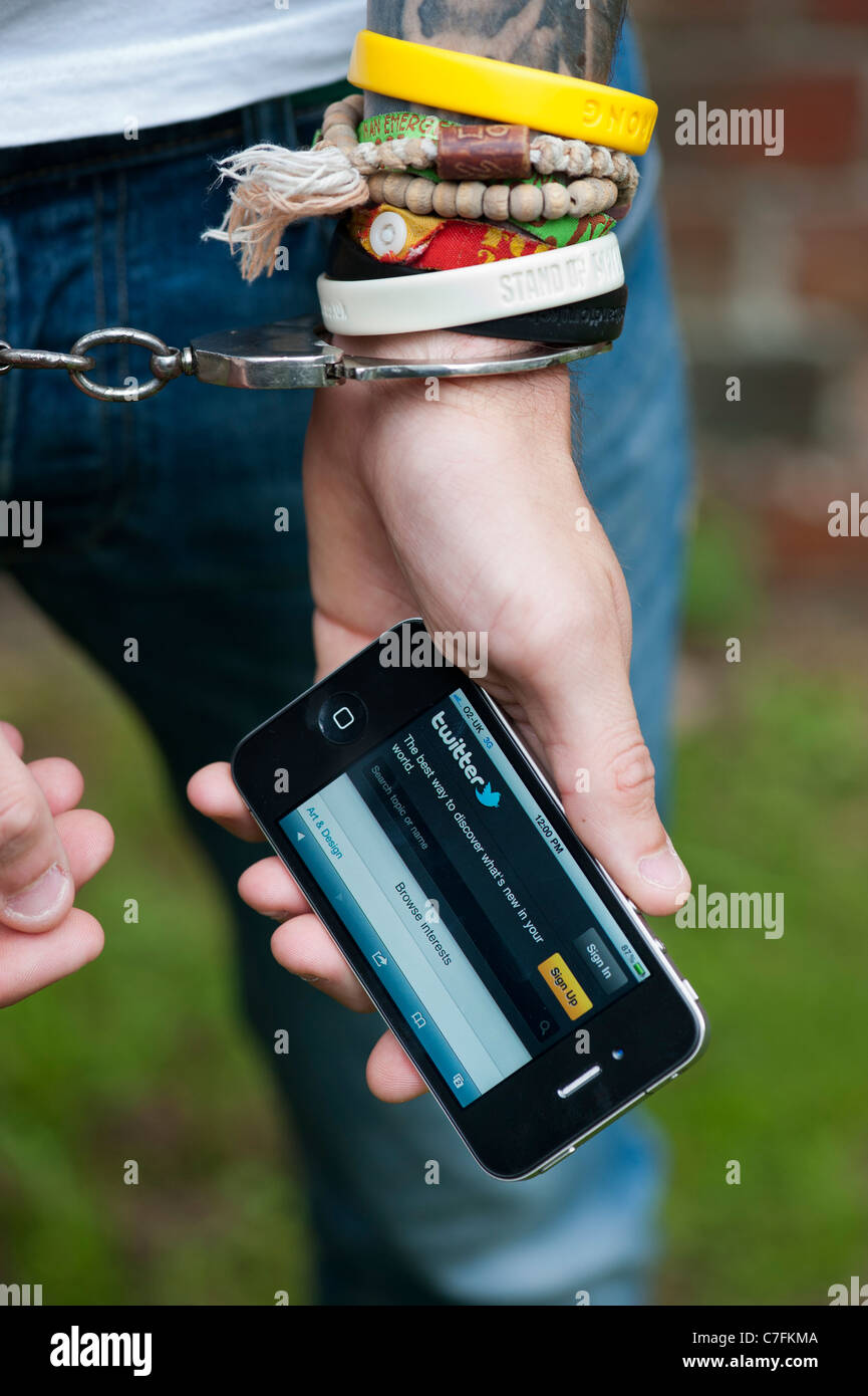 Handcuffed teenager holding an Apple iphone showing Twitter. Stock Photo