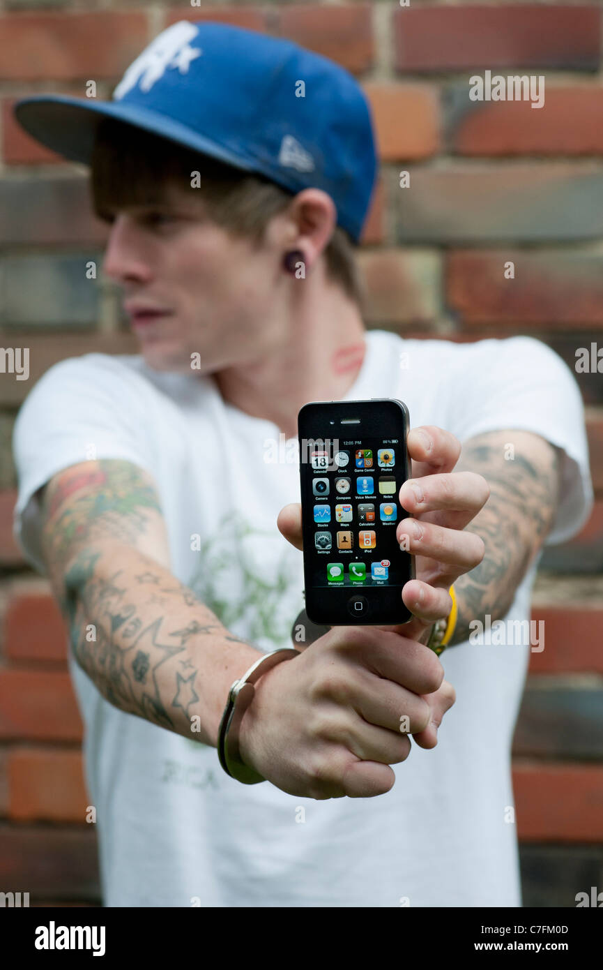 Handcuffed teenager holding an Apple iphone. Stock Photo