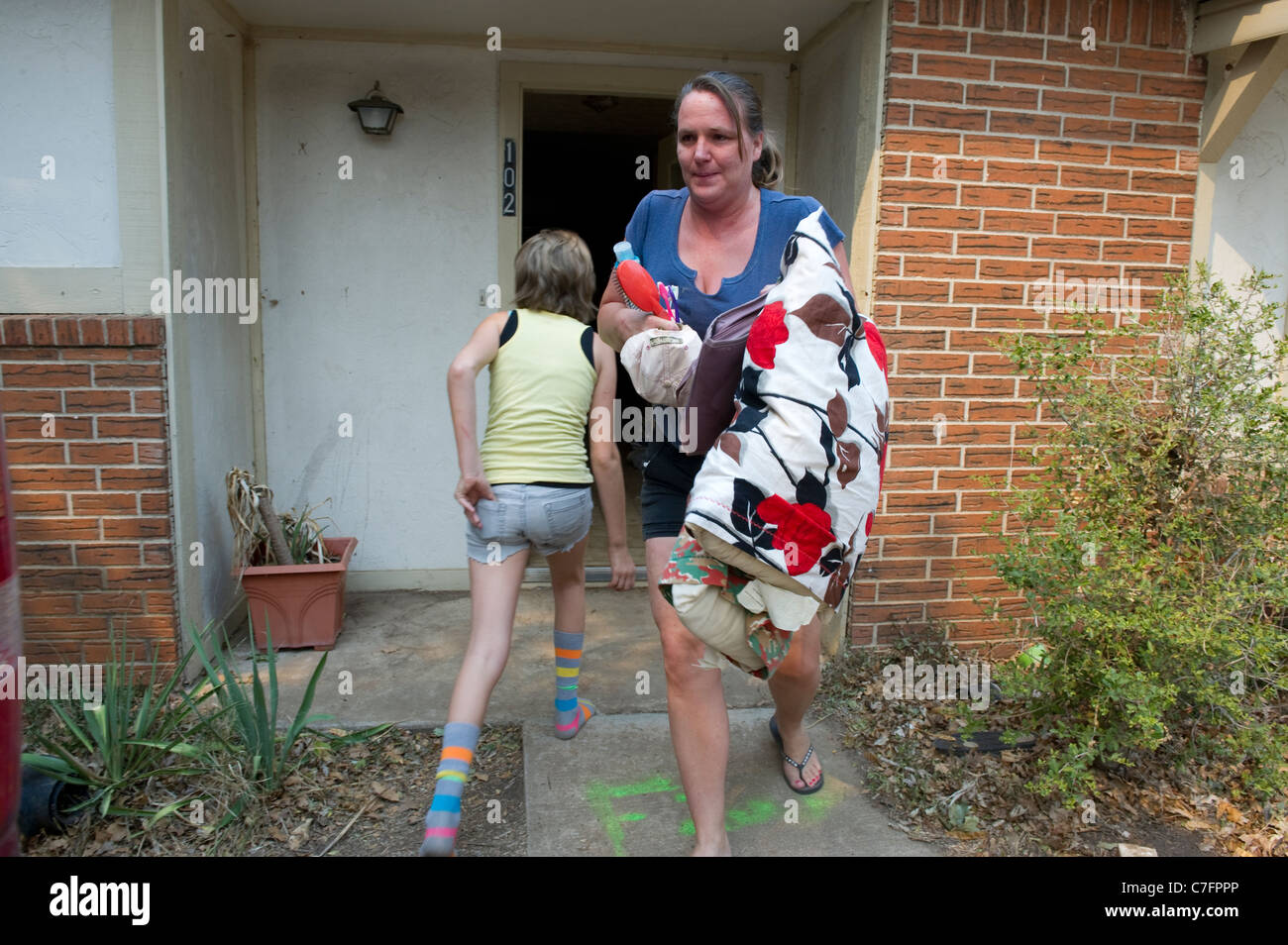 Mom and her daughter rush to get items from home before leaving the area as a wildfire approaches near Bastrop TX Stock Photo