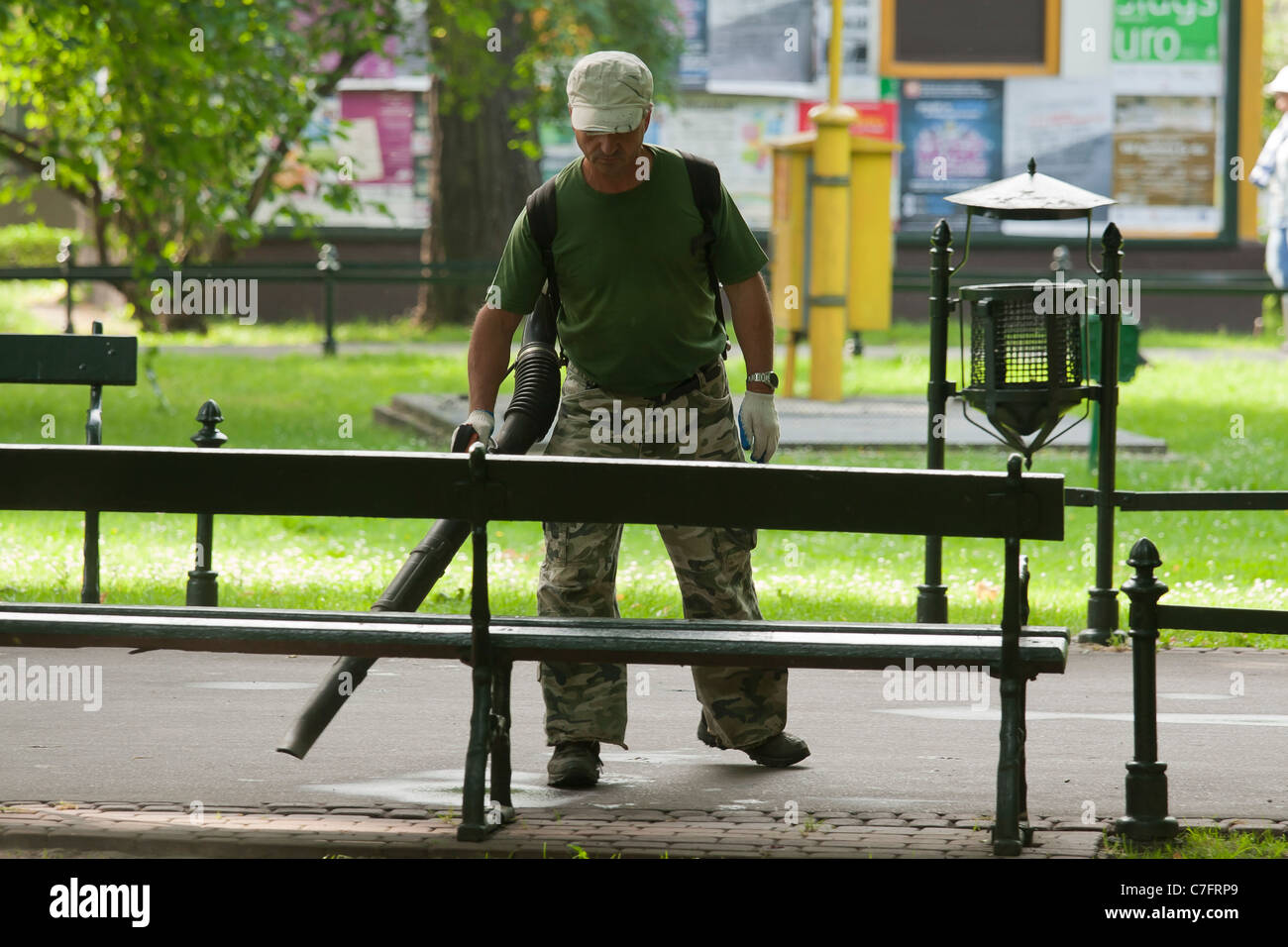Maintenance worker cleaning a park alley using a blower. Krakow, Poland. Stock Photo