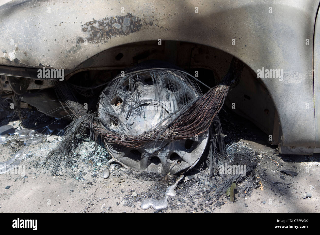 A melted tire and wheel on a car sits outside a home destroyed by wildfire that passed through residential area near Bastrop TX Stock Photo