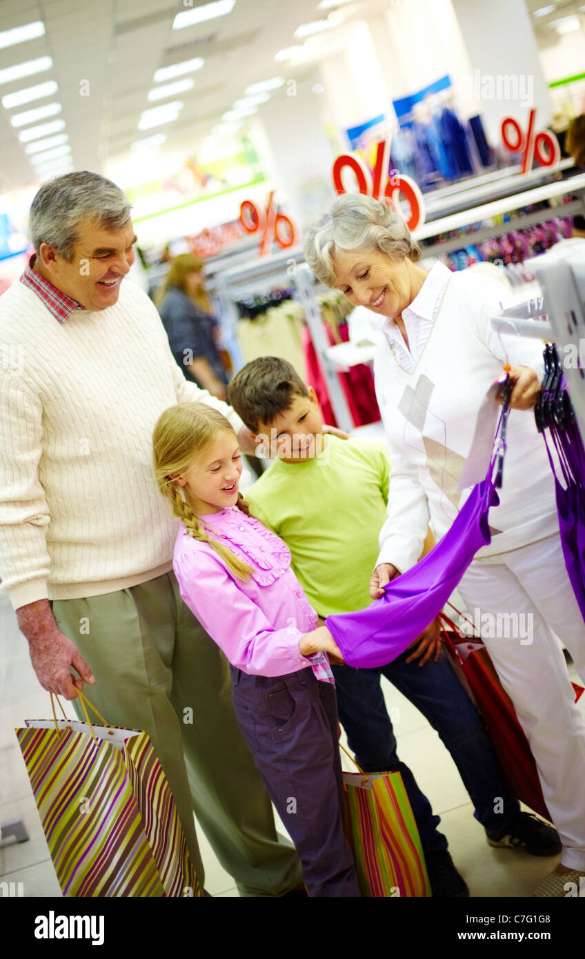 Portrait of happy grandparents and grandchildren choosing clothes in