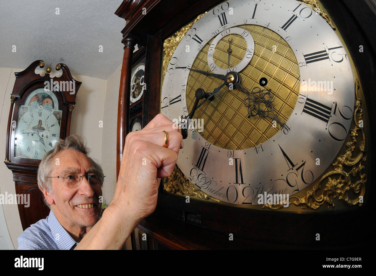 A man adjust the time on an antique clock Stock Photo Alamy