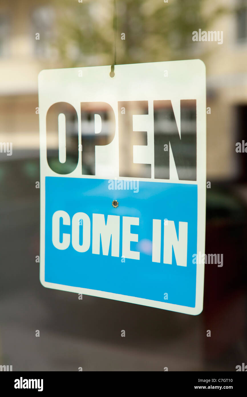 An OPEN COME IN sign hanging in the window of a shop door Stock Photo