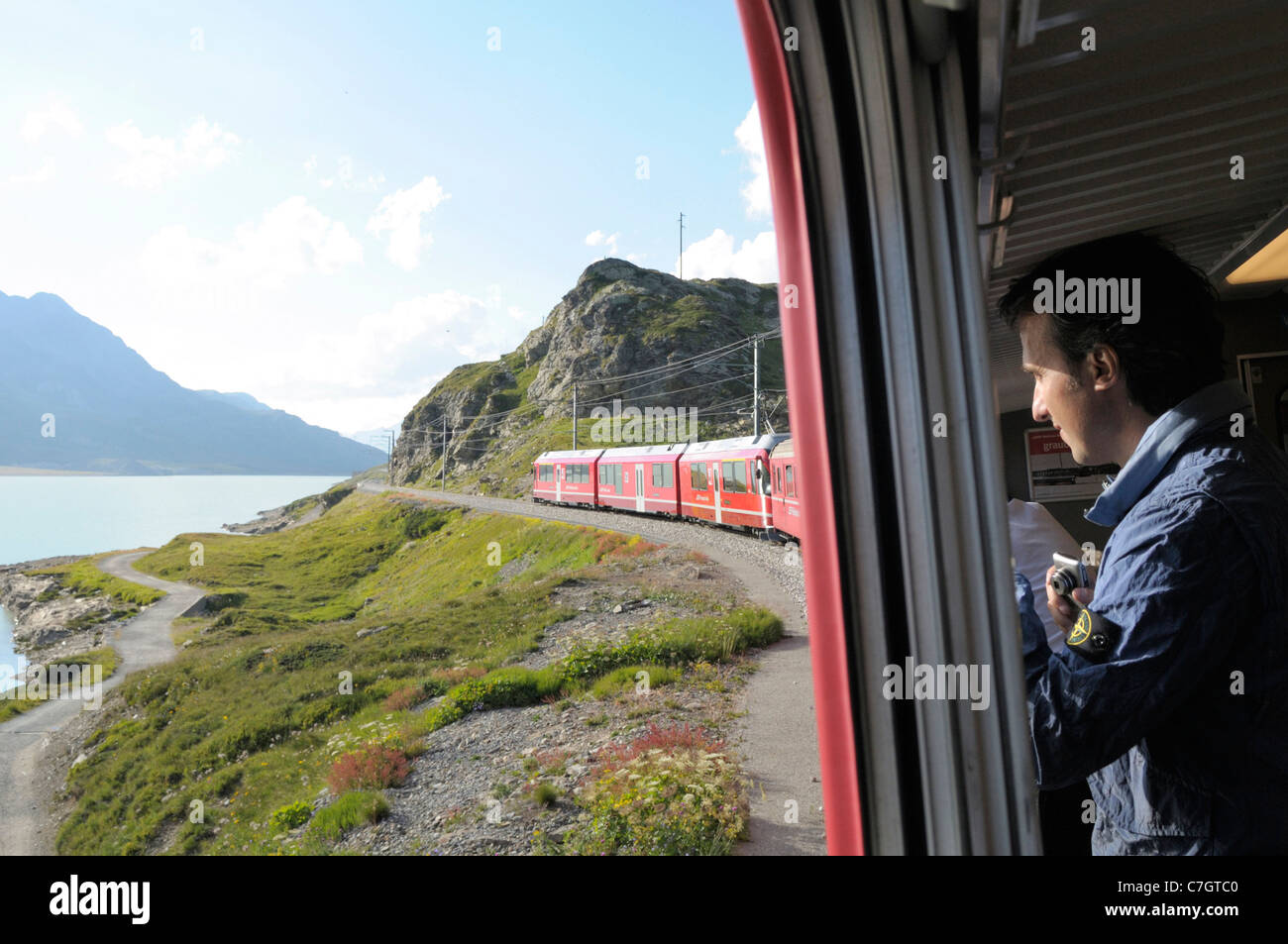Train ride with Rhätische Bahn on the Bernina line from Ospizio Bernina to Poschiavo passing the Lago Bianco. Switzerland. Stock Photo