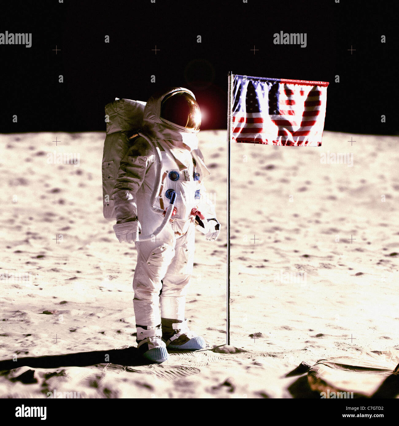 An astronaut next to an American flag on the moon Stock Photo