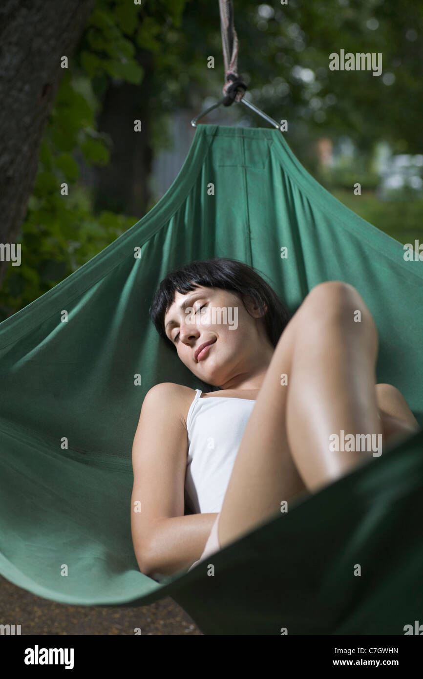 A woman lying in a hammock, eyes closed Stock Photo