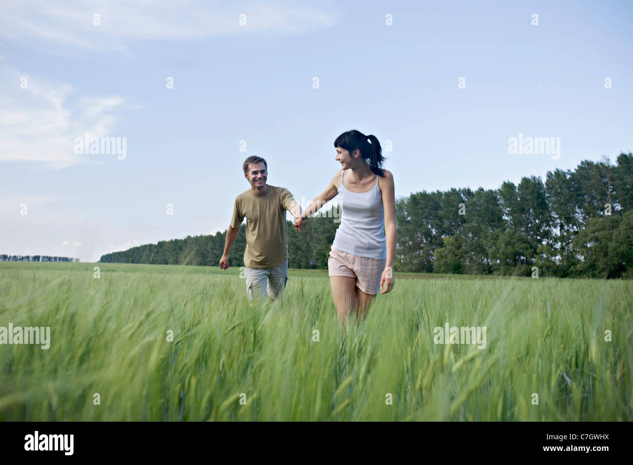 A woman pulling her boyfriend through a field Stock Photo