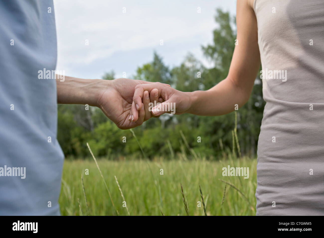A young couple holding hands, midsection Stock Photo