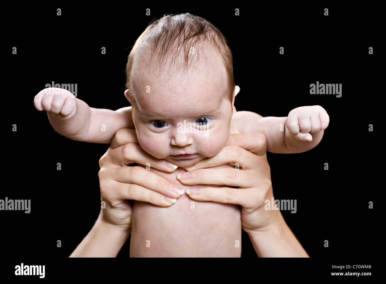 A baby held aloft staring down Stock Photo