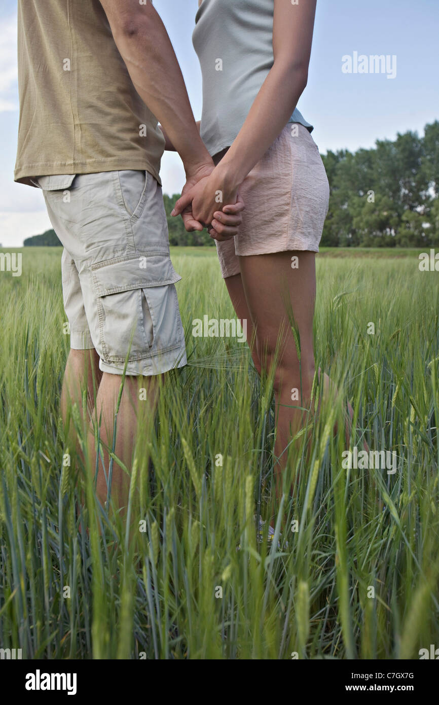 A young couple holding hands, standing in a field Stock Photo
