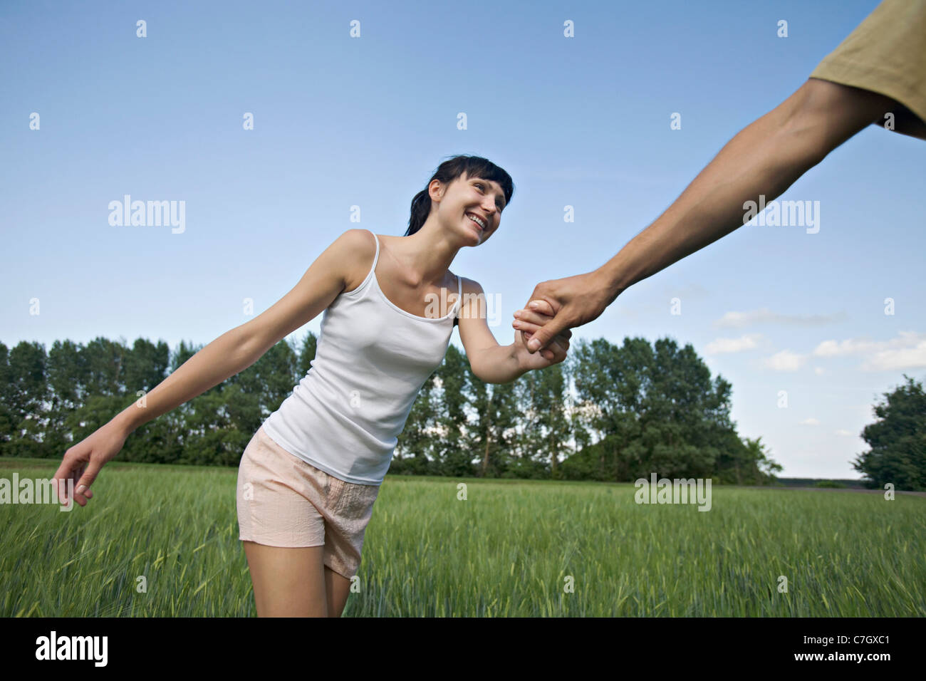 A man pulling his girlfriend through a field Stock Photo