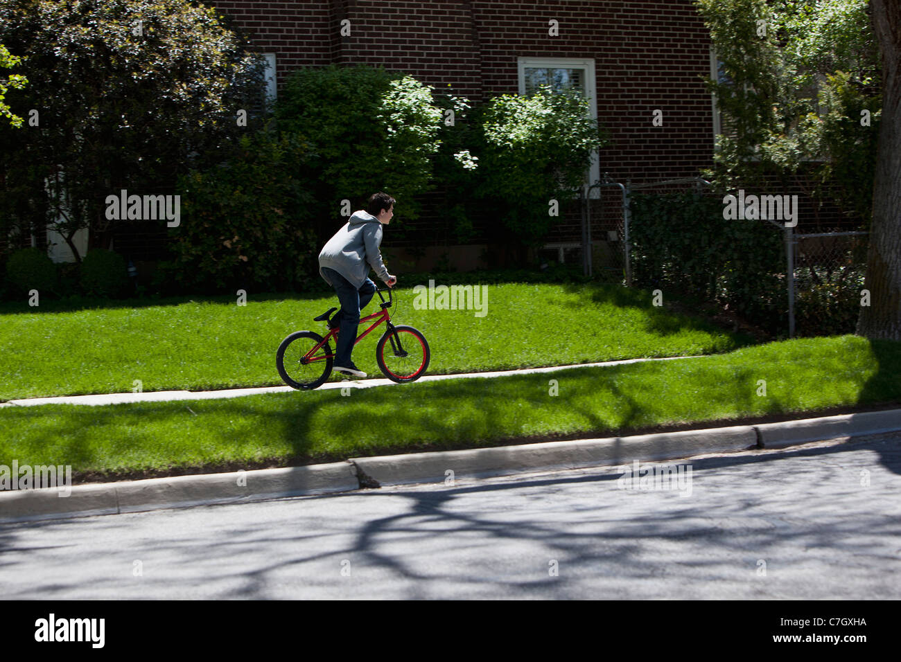 Boy stands while riding bike on footpath Stock Photo Alamy